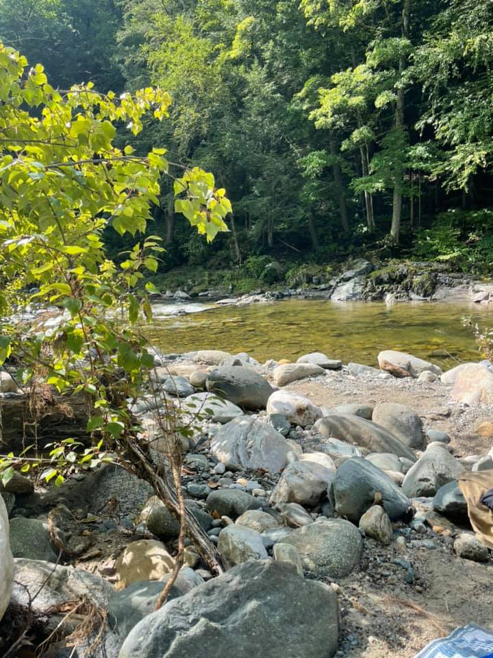 Wading together Couple smiling while wading in clear shallow Rock River water in Newfane, Vermont — smooth stones and summer forest