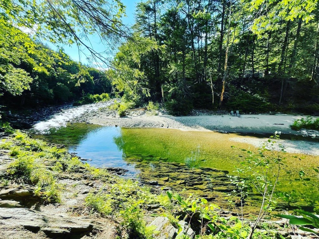 Rock River — clear pools and beach, summer Clear turquoise water of Rock River in Newfane, Vermont, winding past a small sandy beach with chairs, lush green forest on a bright summer day — Windham County swimming hole